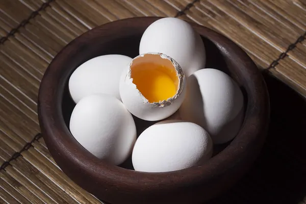 A bowl of eggs with one cracked open, a common food source of riboflavin